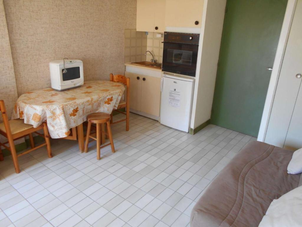 eine kleine Küche mit einem Tisch und einer Mikrowelle in der Unterkunft Appartement Le Grau-du-Roi, 1 pièce, 4 personnes - FR-1-250-179 in Le Grau-du-Roi