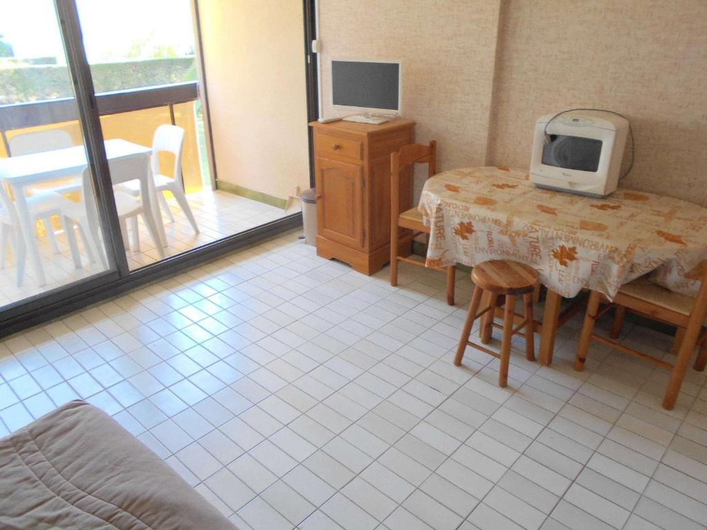 Zimmer mit einem Tisch und einem TV in der Unterkunft Appartement Le Grau-du-Roi, 1 pièce, 4 personnes - FR-1-250-179 in Le Grau-du-Roi