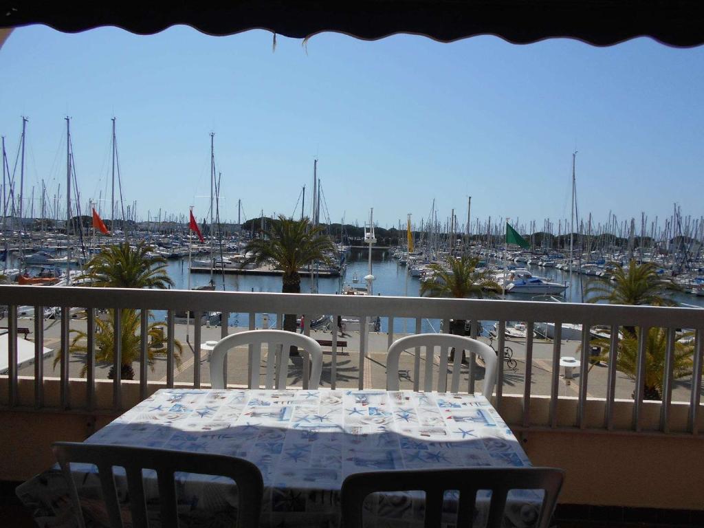 un balcon avec une table et des chaises et un port de plaisance dans l'établissement Appt climatisé 4 pers avec parking à Port Camargue - FR-1-250-206, au Grau-du-Roi
