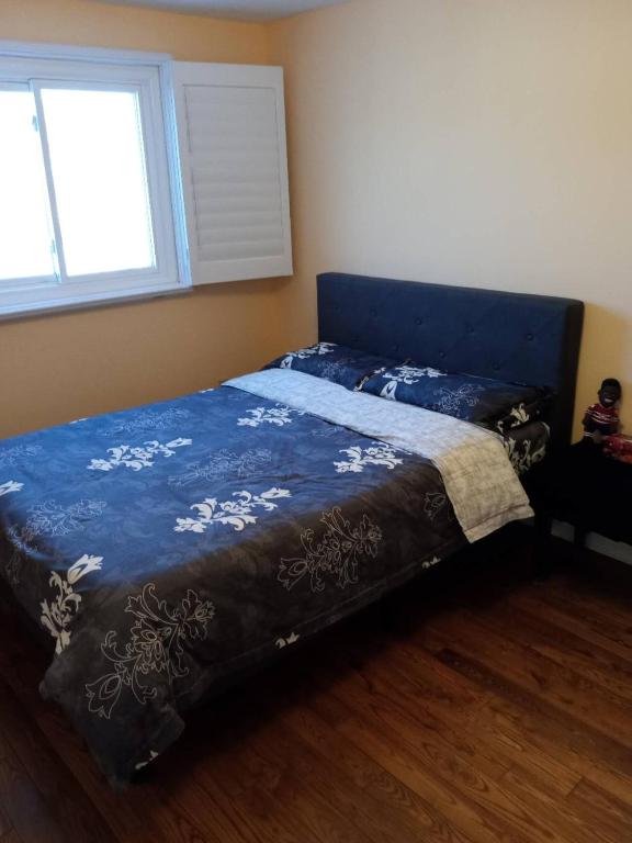 a bedroom with a bed with a blue comforter and a window at Fancy home in Richmond hill in Richmond Hill