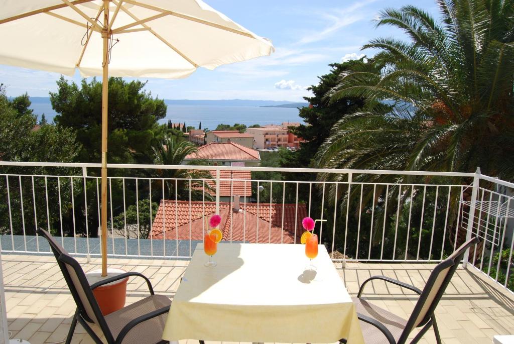 a table and chairs with an umbrella on a balcony at Palma Promajna Apartments in Promajna