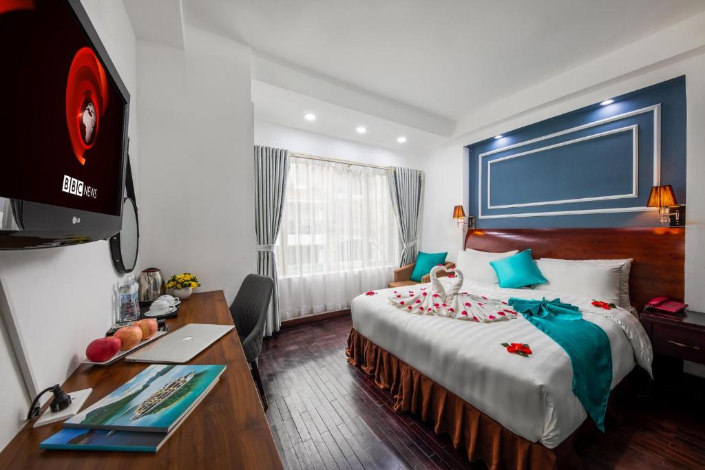 Habitación de hotel con cama, escritorio y TV. en Hanoi Sisters Boutique Hotel, en Hanói