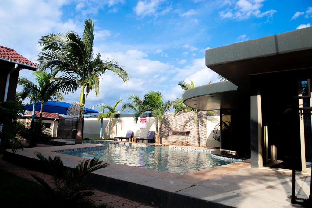 una piscina frente a una casa con palmeras en EMC Fully Furnished &Serviced Apartments 4 bedroom with a private Pool, Wifi ,Aircons & Dstv, en Lusaka