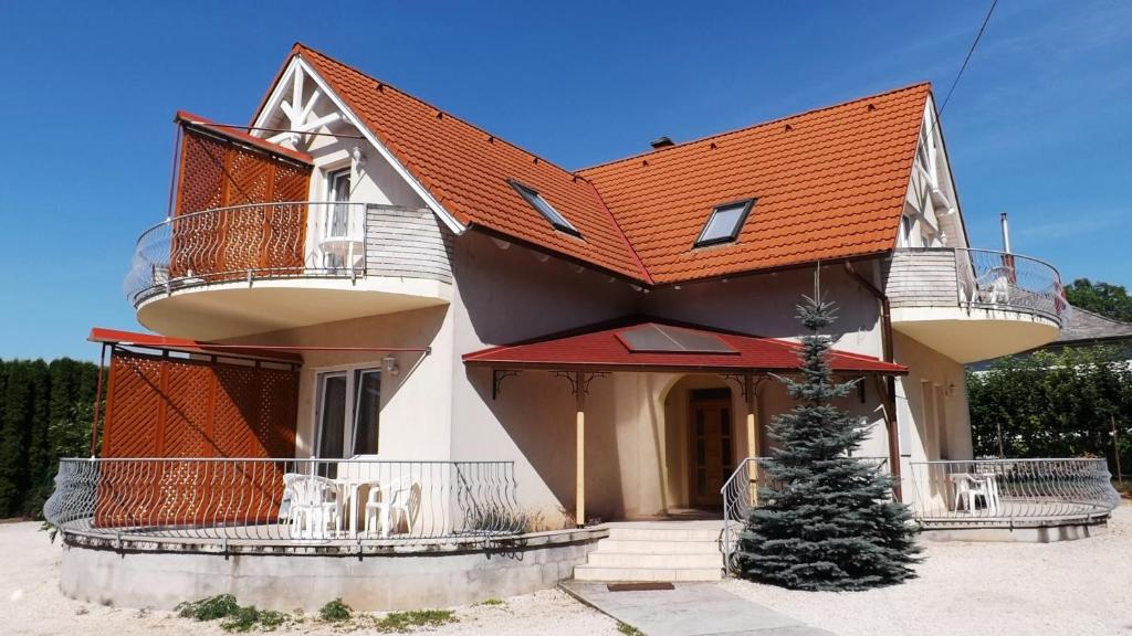 una casa con techo naranja con un árbol de Navidad delante en Klassz Apartmanház, en Balatonfüred