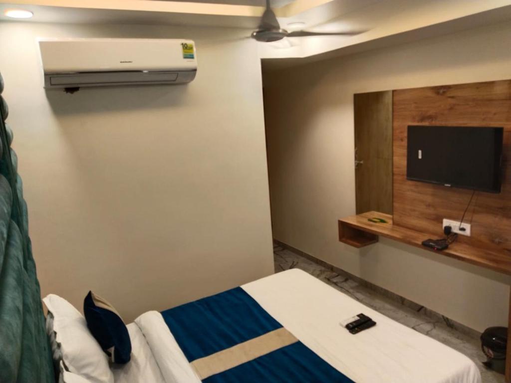 a hotel room with a bed and a flat screen tv at Hotel Skyland in Ahmedabad