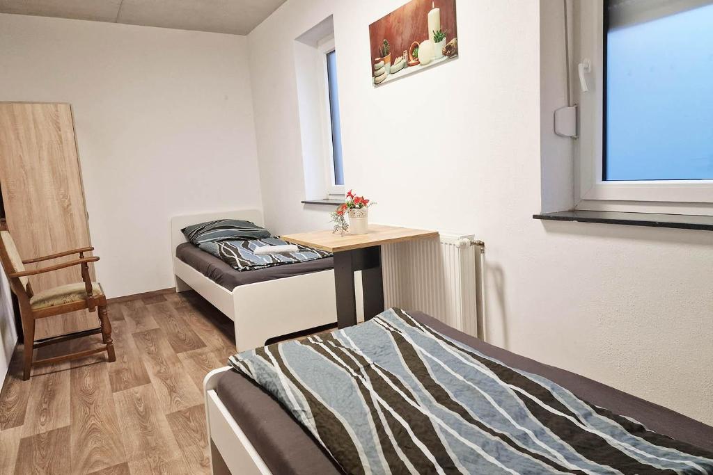Cette chambre comprend deux lits, une table et une chaise. dans l'établissement Work & Stay in Kranenburg near Kleve, à Kranenburg