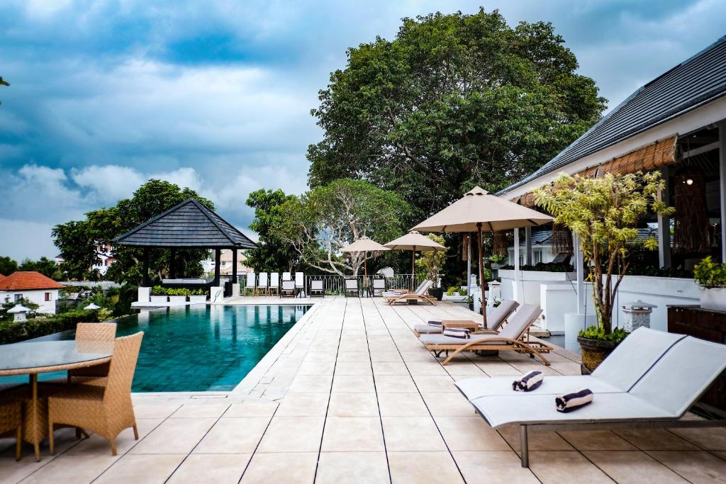 a pool at a resort with chairs and umbrellas at Villa Puri Balangan in Uluwatu