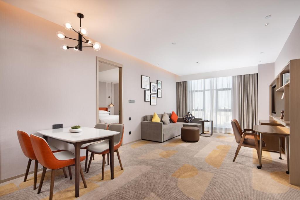 un soggiorno con tavolo, sedie e divano di Home2 Suites By Hilton Shenzhen Dalang a Shenzhen