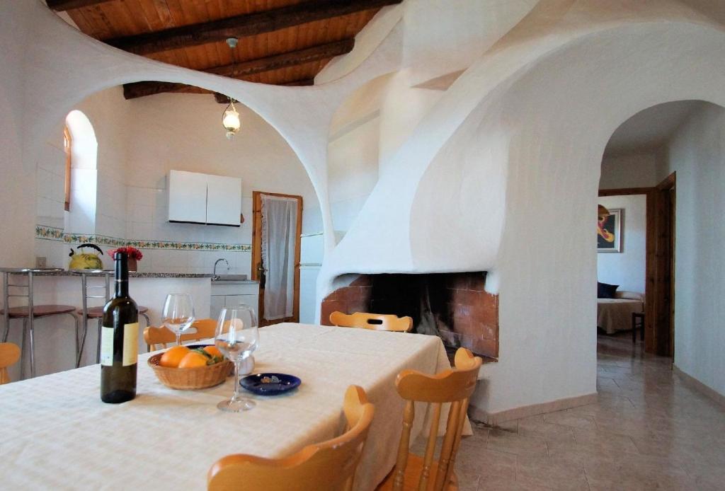 - une salle à manger avec une table et une bouteille de vin dans l'établissement Tolles Ferienhaus in La Ciaccia mit Möblierter Terrasse, à Valledoria