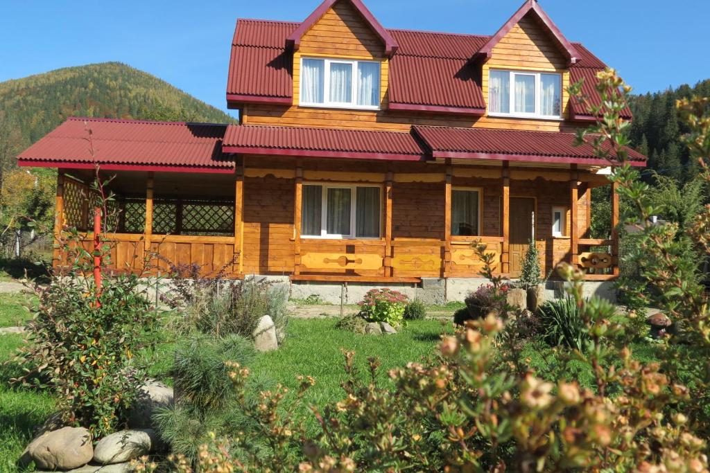 Casa de madera con techo rojo en Bilyy Kamin Guest House en Tatariv