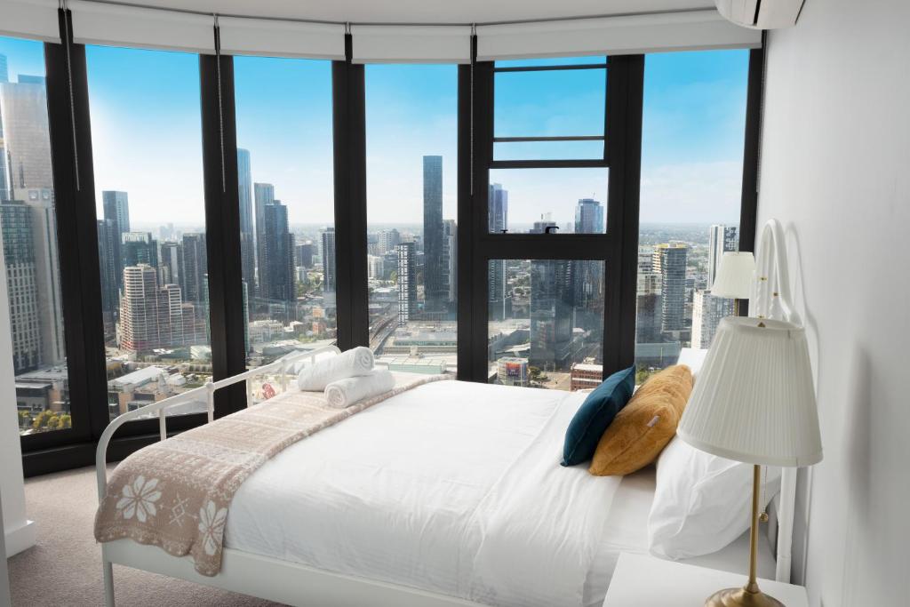 a bedroom with a white bed and a large window at Pars apartments - Melbourne Quarter- unique View of city and Yarra in Melbourne