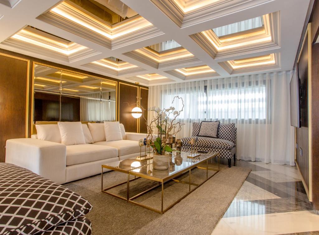 Makass Appart Hotel في الرباط: غرفة معيشة مع أريكة بيضاء وطاولة