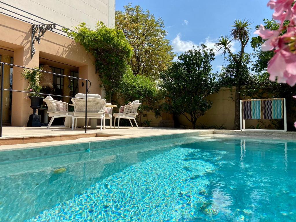 a swimming pool with a table and chairs next to a house at Le Gabriel in Claviers