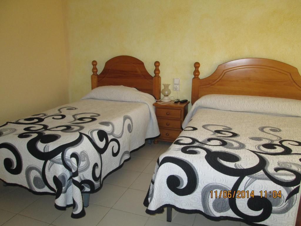 1 dormitorio con 2 camas y mesita de noche con faldas en Pensio l'Avi Pep en Saus