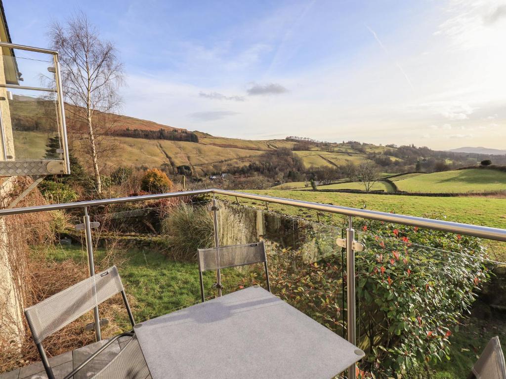 a balcony with two chairs and a view of the countryside at Haystacks in Troutbeck