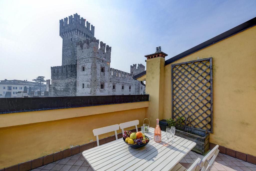 a table with a bowl of fruit on a balcony with a castle at Sunset Apartment Home & Terrace in Sirmione