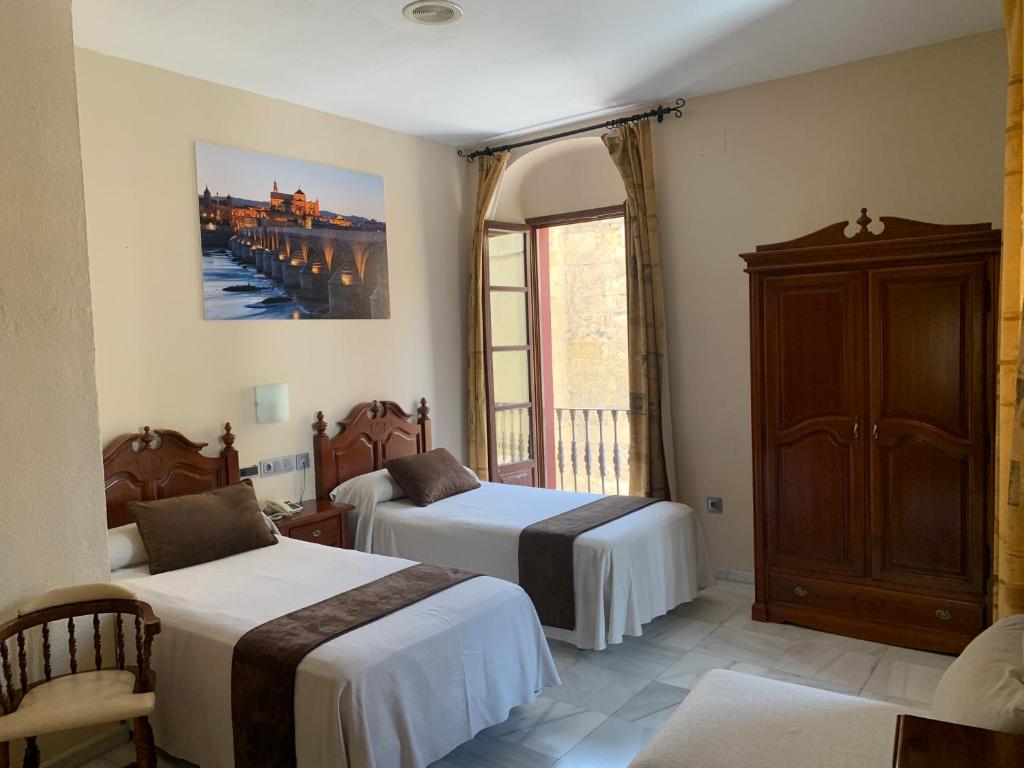 a hotel room with two beds and a window at Hotel Casa Museo de la Mezquita in Córdoba