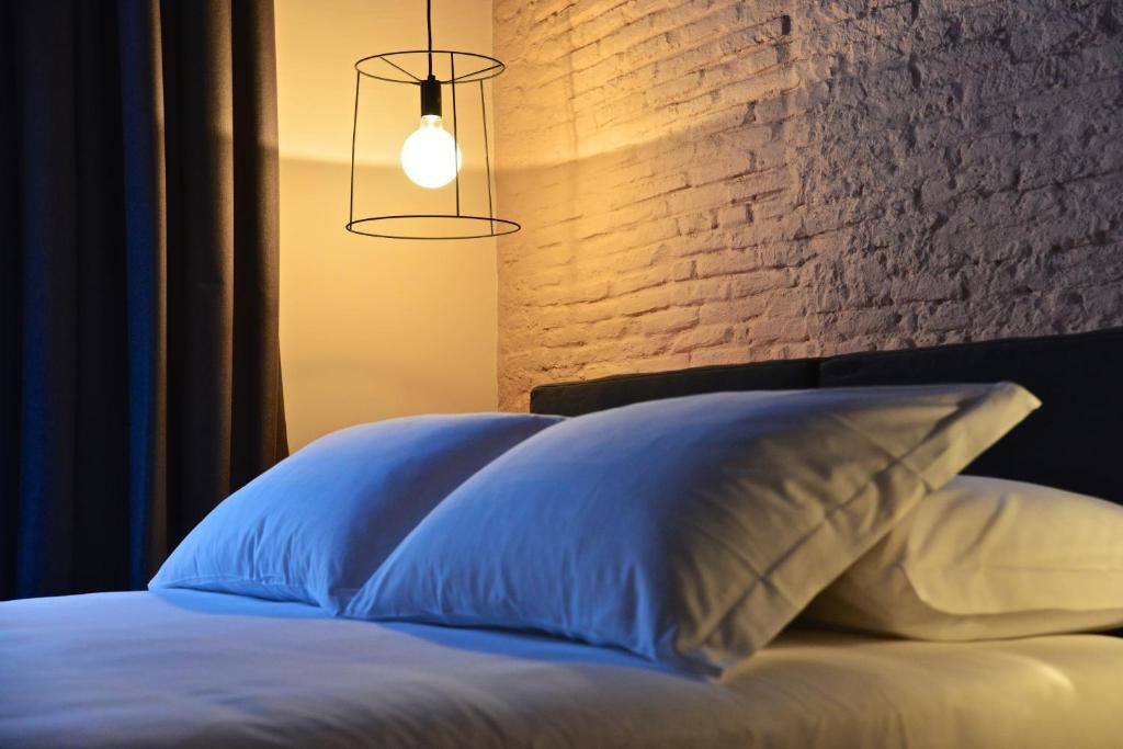 łóżko z 2 białymi poduszkami i ceglaną ścianą w obiekcie Palais La Nasse w San Remo