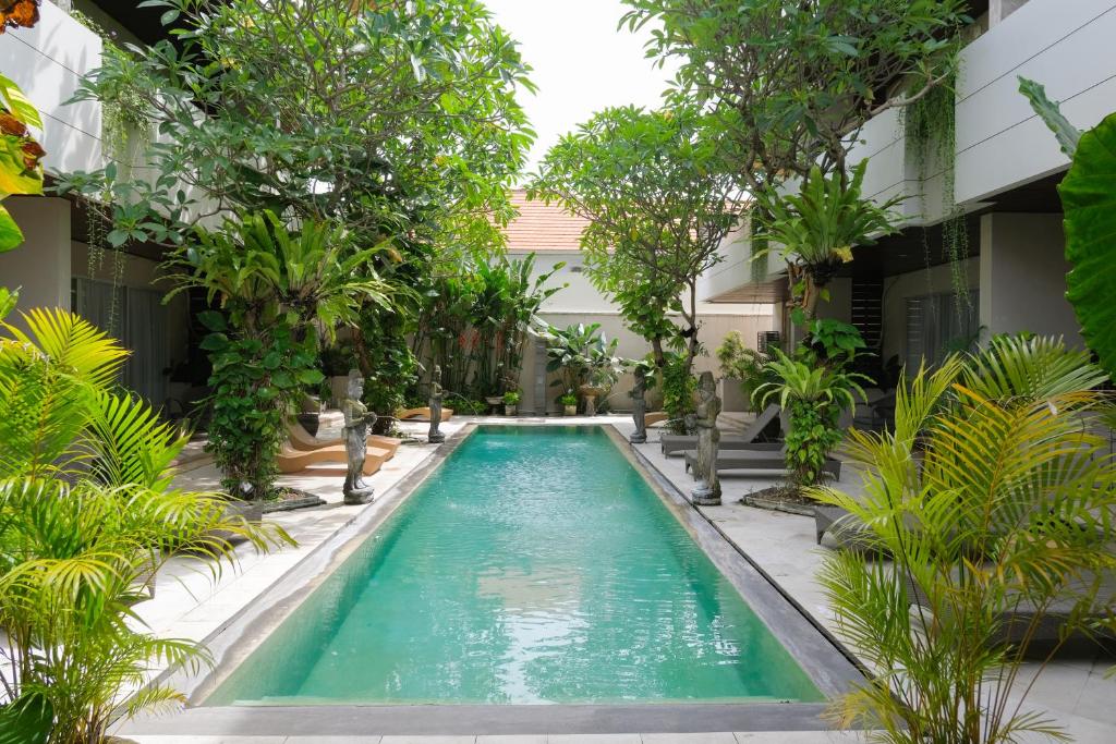 a swimming pool in the middle of a building with trees at Sunset Mansion Seminyak in Seminyak