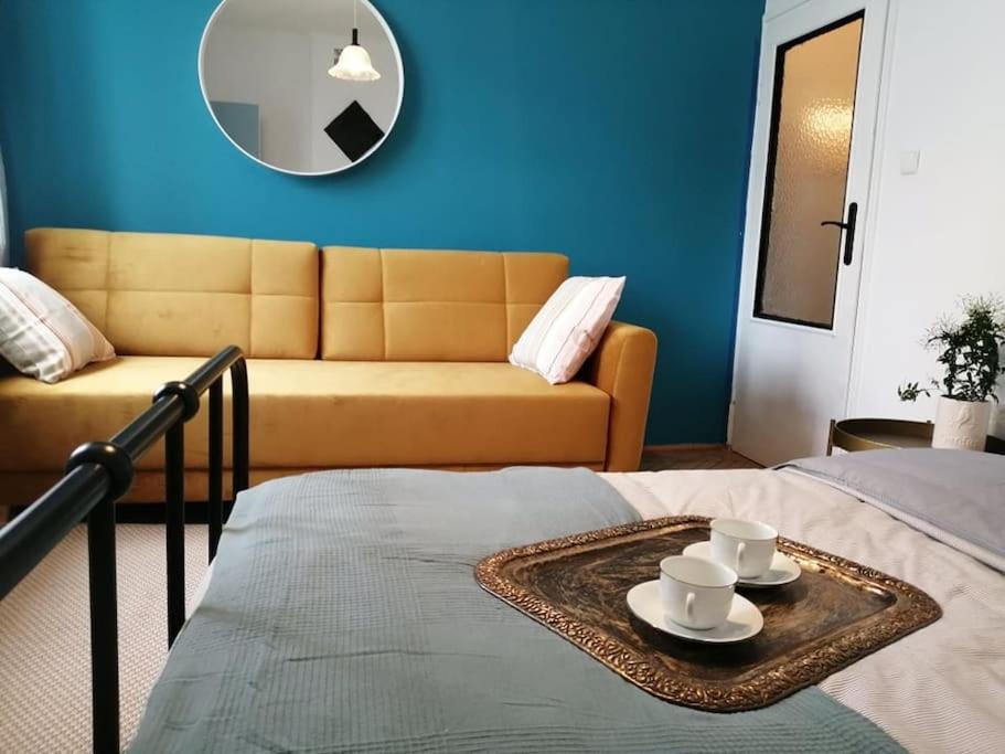 Habitación con cama con 2 tazas y sofá en Klimatyczne mieszkanie w doskonałej lokalizacji, en Varsovia