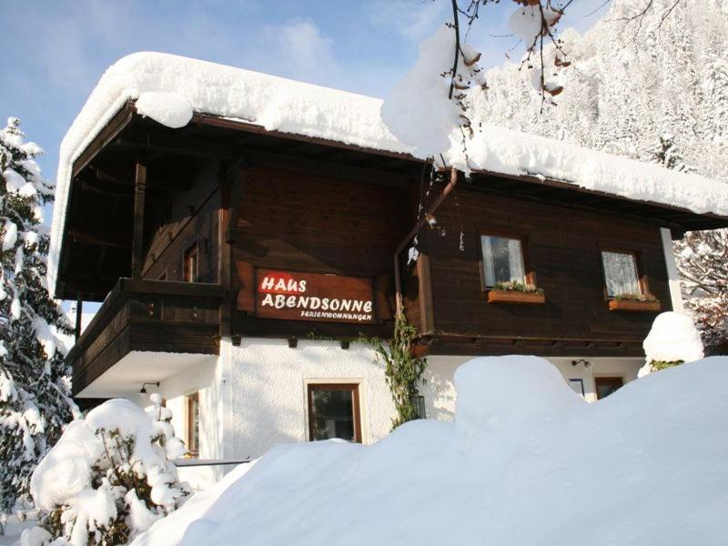 ein schneebedecktes Gebäude mit einem Schild darauf in der Unterkunft Haus Abendsonne in Reit im Winkl
