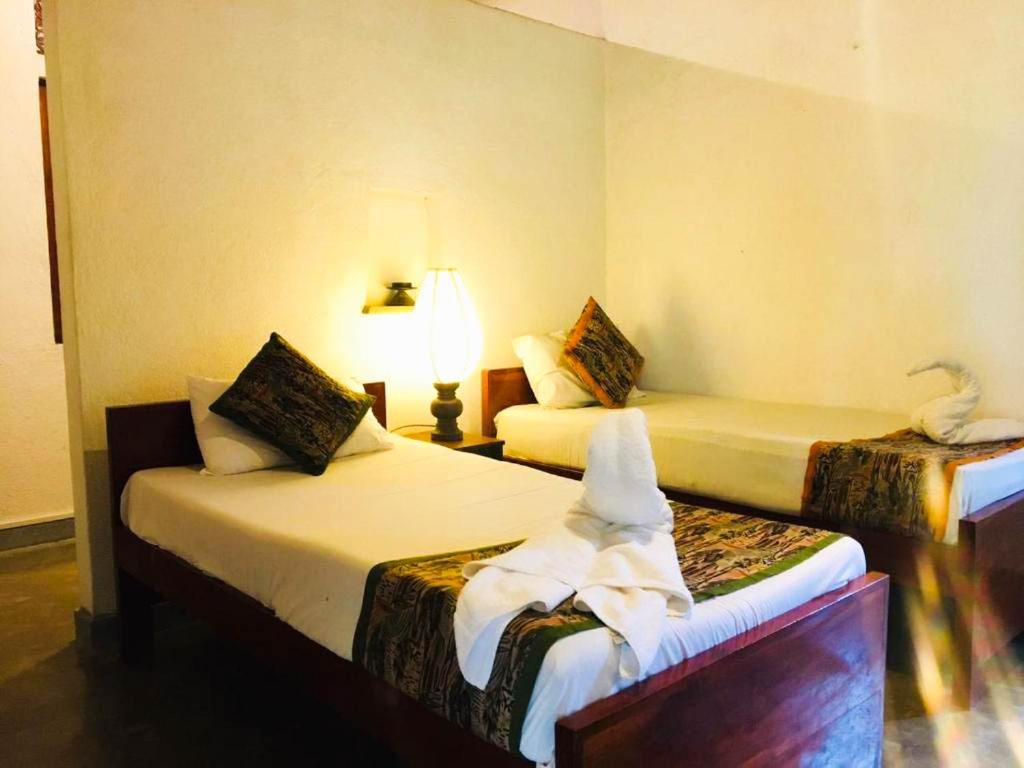 a hotel room with two beds and a lamp at Eth Mansala in Sigiriya