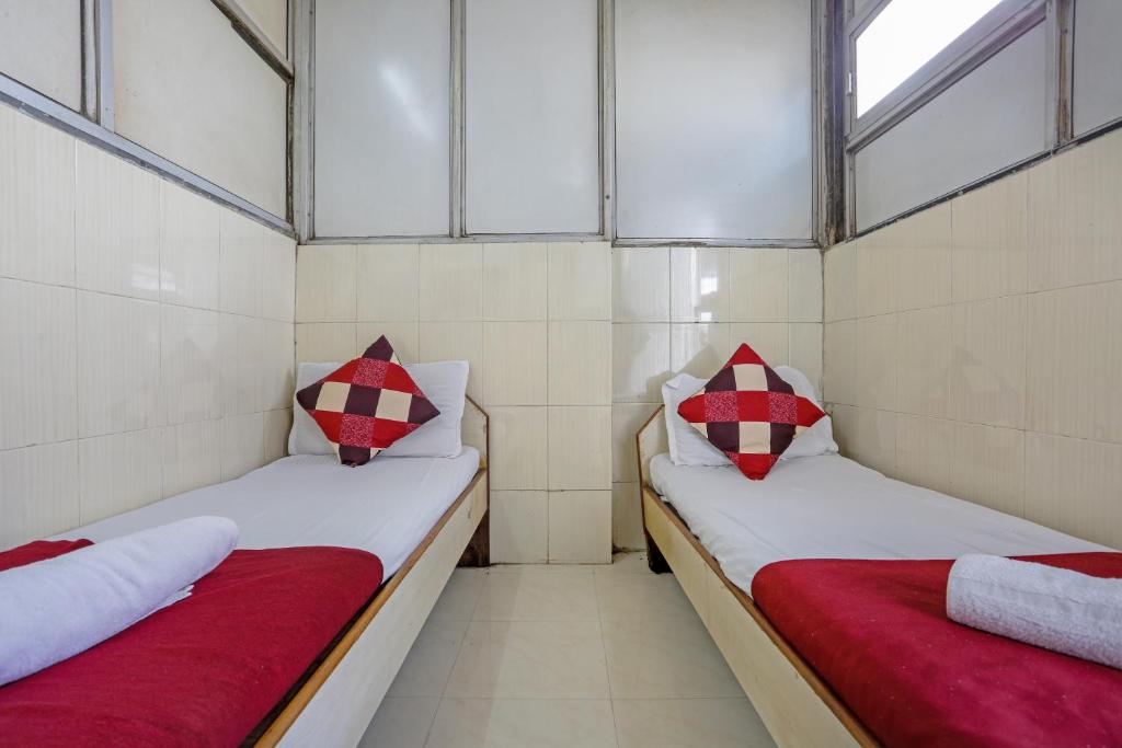 two beds in a small room with red and white pillows at Terminus Hotel Bandra in Mumbai