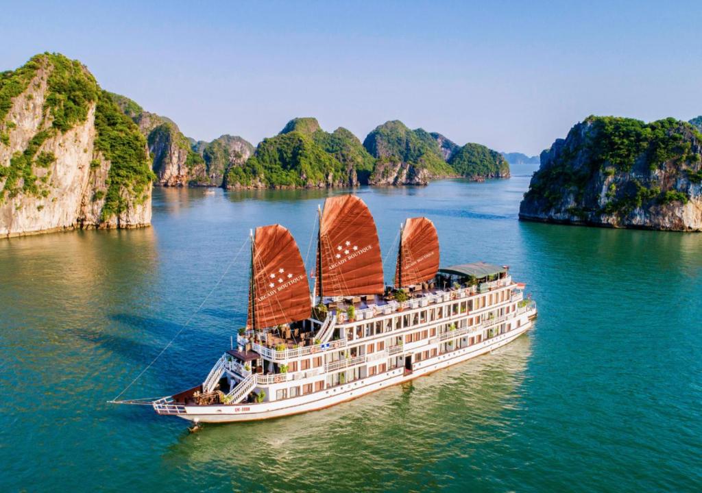 Arcady Boutique Cruise في ها لونغ: سفينة سياحية في خليج هالونج مع منحدرات من الحجر الجيري