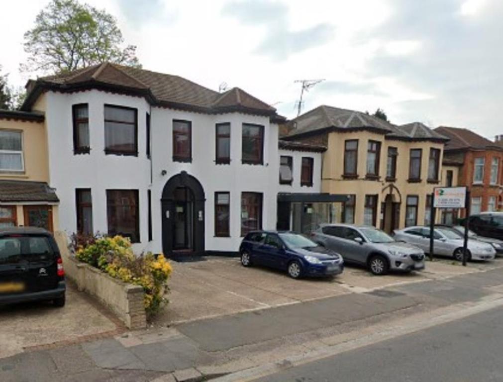 una casa blanca con coches aparcados en un estacionamiento en Saji Hotel Illford en Ilford