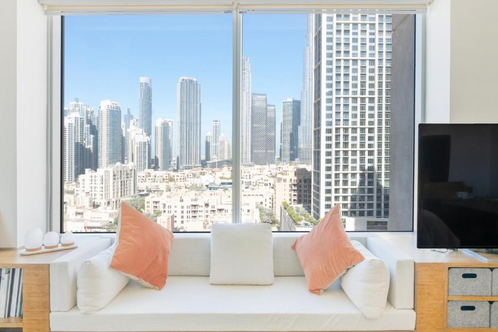 een woonkamer met een witte bank en een groot raam bij Burj Views Tower 2, Downtown- 2BR Apartment - Allsopp&Allsopp in Dubai