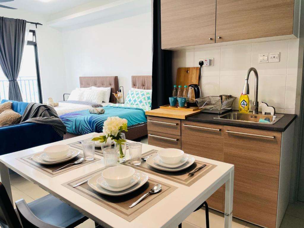 a kitchen and living room with a table with plates on it at High Floor studio Austin Regency Mount Austin w Balcony 3 plus 1pax 5 mins AEON in Johor Bahru