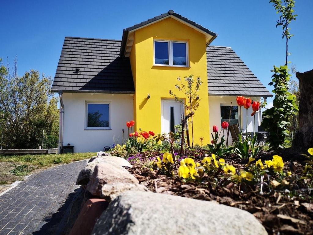 una casa amarilla con flores delante en Familienfreundliches ruhig gelegenes perfekt ausgestattetes Ferienhaus, en Boiensdorf