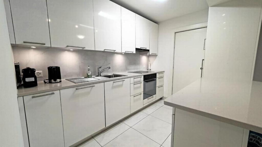 una cocina blanca con armarios blancos y fregadero en Süsse Wohnung Apt 106 en Locarno