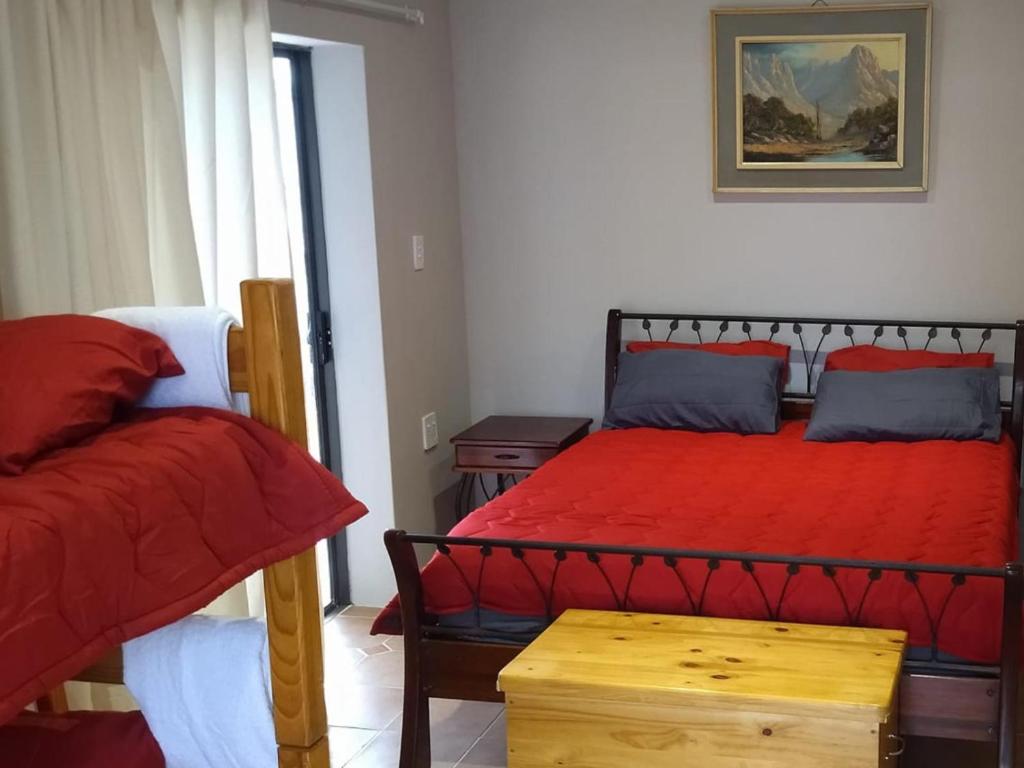 a bedroom with a bed with red sheets and a table at Royal Karoo Cottage unit 1 in Beaufort West