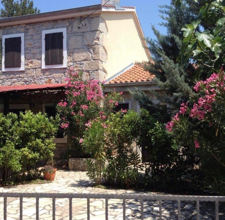 a house with pink flowers in front of a fence at Apartman Heidi 4 Sterne in Punat