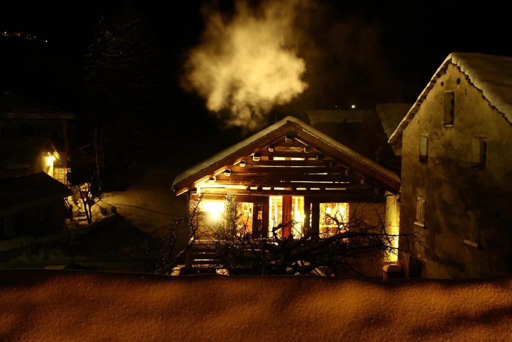 ein Haus mit Rauch, der nachts aus ihm rauskommt in der Unterkunft La Stalla in Vicosoprano