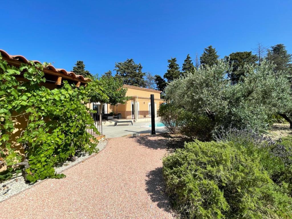 ogród z krzakami i drzewami oraz budynek w obiekcie Beau studio en duo au coeur du Luberon w mieście Saumane-de-Vaucluse