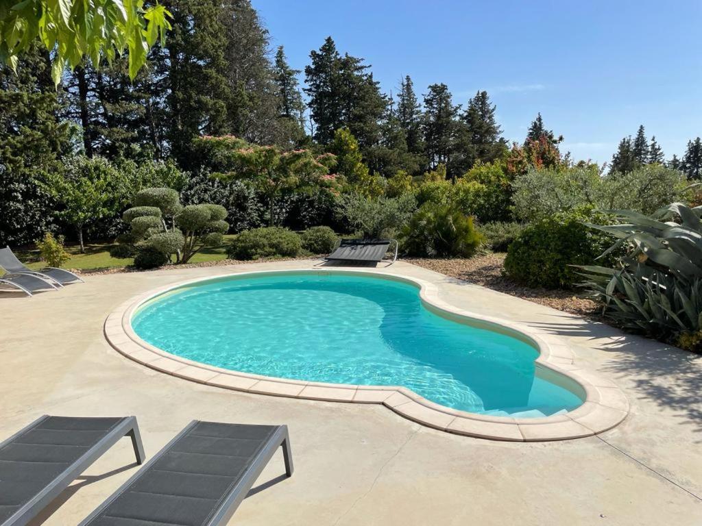 basen w ogrodzie z dwoma krzesłami wokół niego w obiekcie Beau studio en duo au coeur du Luberon w mieście Saumane-de-Vaucluse