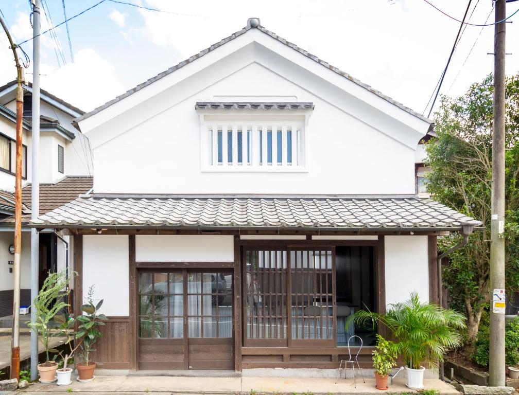 een wit huis met houten deuren bij Akizuki OKO art&inn in Asakura