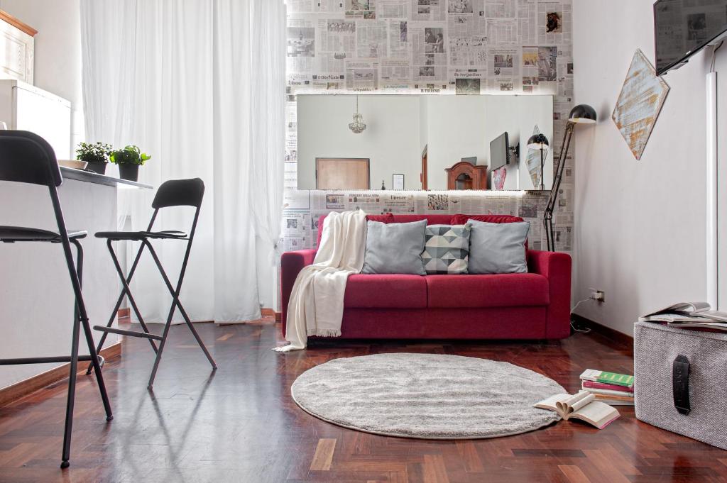 un soggiorno con divano rosso e tappeto di The Journalist House a Livorno