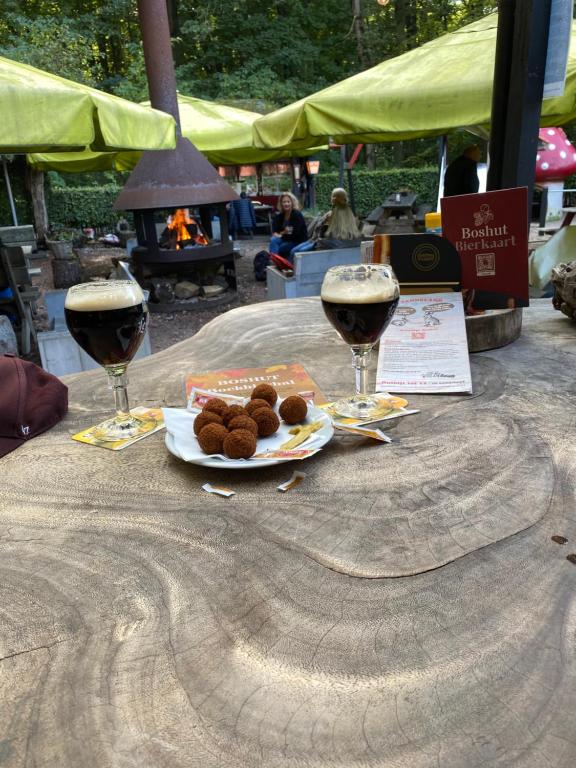 een tafel met twee glazen wijn en een bord eten bij Appartement Bos en Duin in Vogelenzang