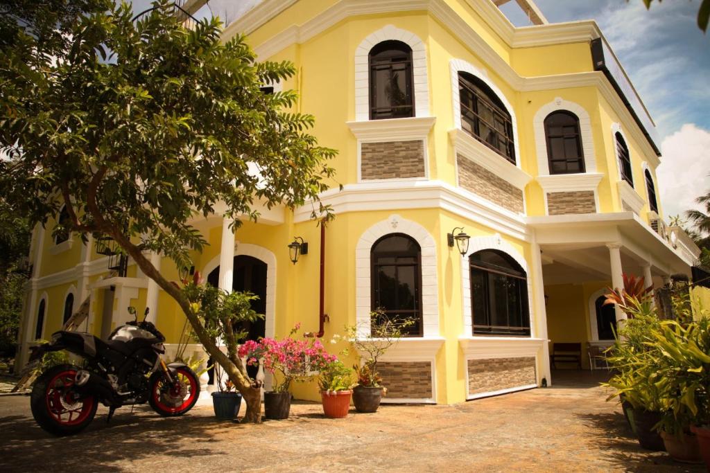 een geel huis met een motorfiets er voor geparkeerd bij Villa Italia Hotel in Sorsogon
