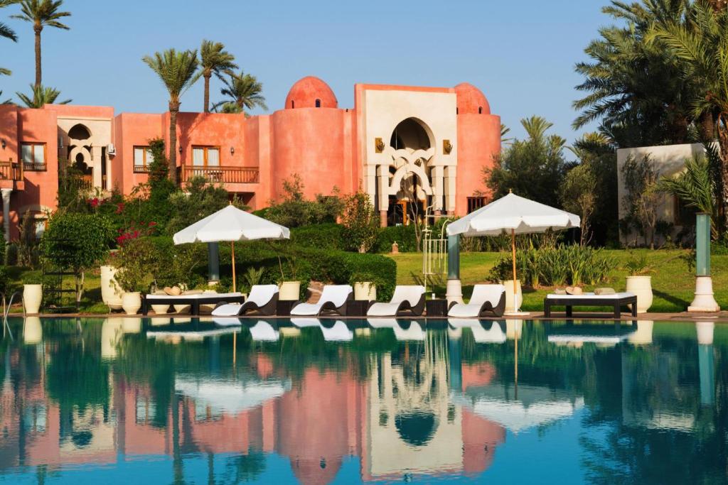un complexe doté d'une piscine avec des chaises longues et des parasols dans l'établissement Palais Mehdi, à Marrakech