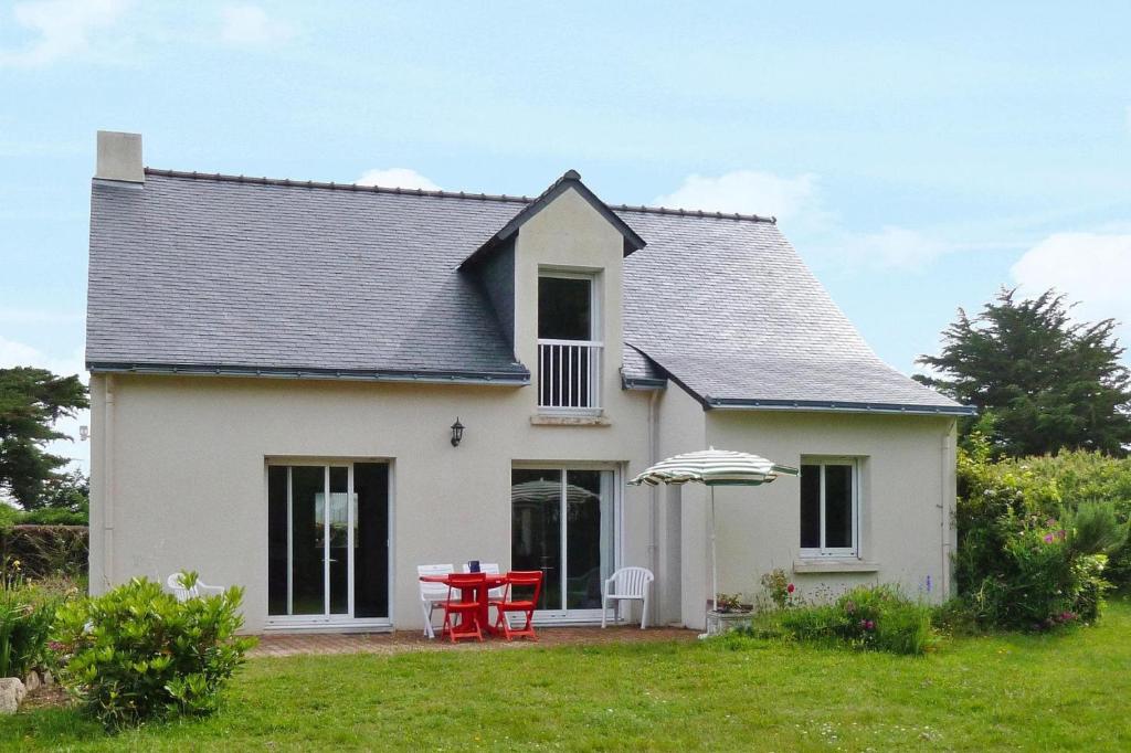 uma casa branca com uma mesa vermelha e um guarda-chuva em Holiday Home Piriac-sur-Mer - NAT01027-F em Piriac-sur-Mer