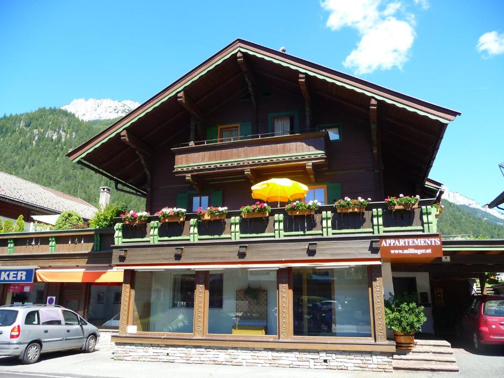 a building with a balcony with flowers and an umbrella at Millinger Appartements in Waidring