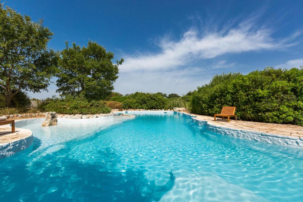 una piscina con panchina e acqua blu di Trulli di Monte Reale by BarbarHouse a Cisternino