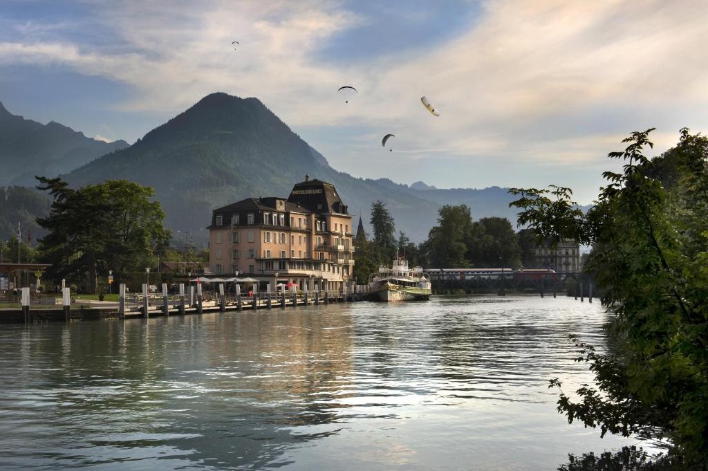 a river with a building and birds flying over it at Hotel Du Lac in Interlaken