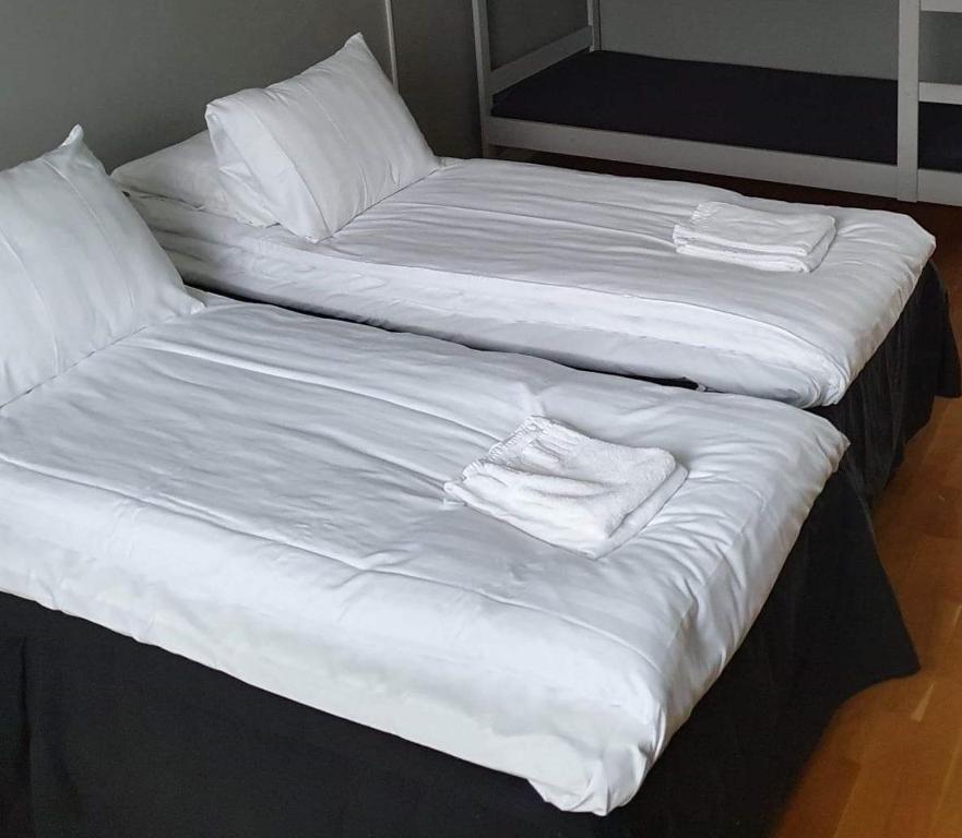 two beds with white sheets and towels on them at Hotell Eskilstuna in Eskilstuna