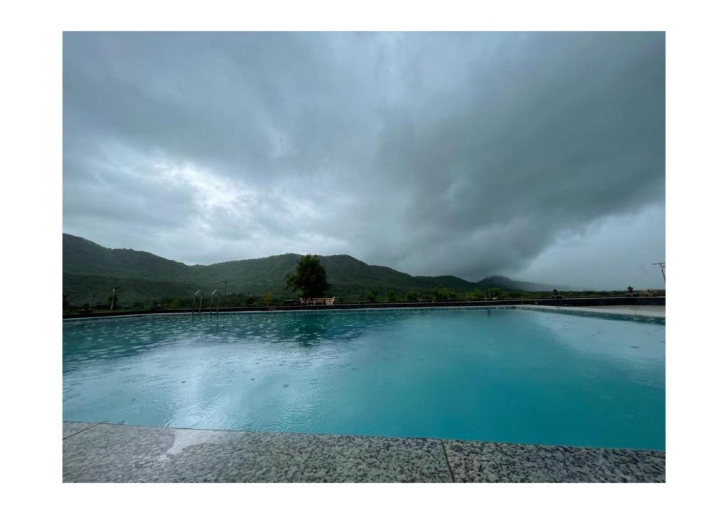 a large pool of water with mountains in the background at Dice Villa rooms in Alibaug