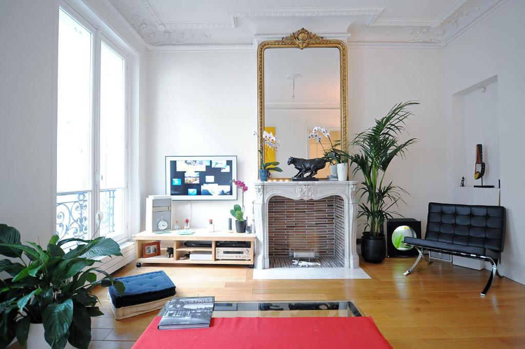sala de estar con chimenea y espejo en Champs Elysees Homestay - AIR CONDITIONING, en París